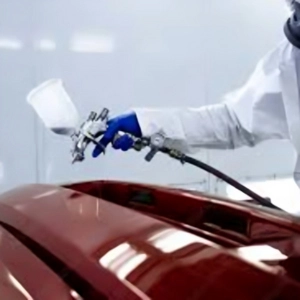 A technician painting a car in red